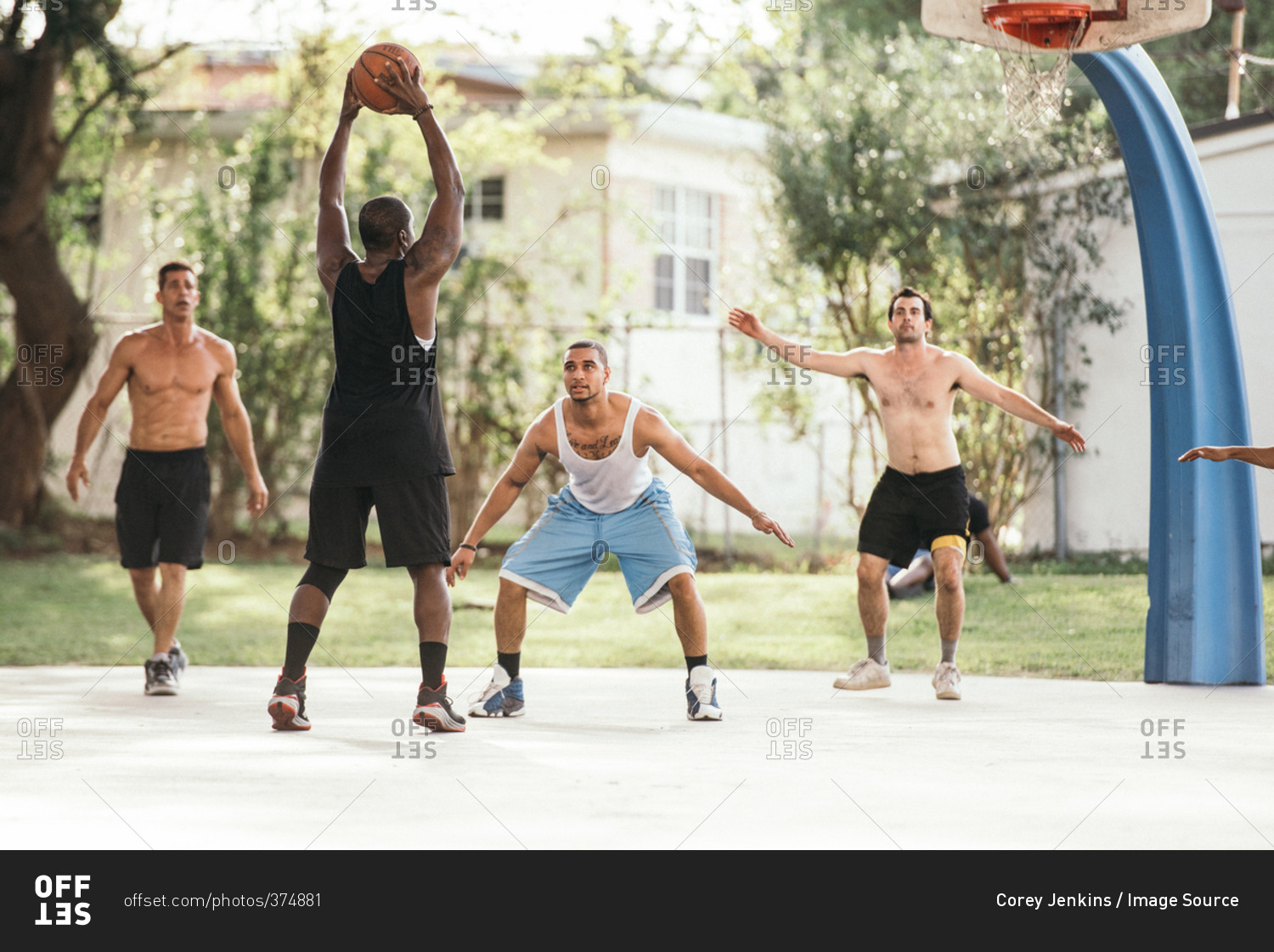 Men on basketball court playing basketball, defending hoop