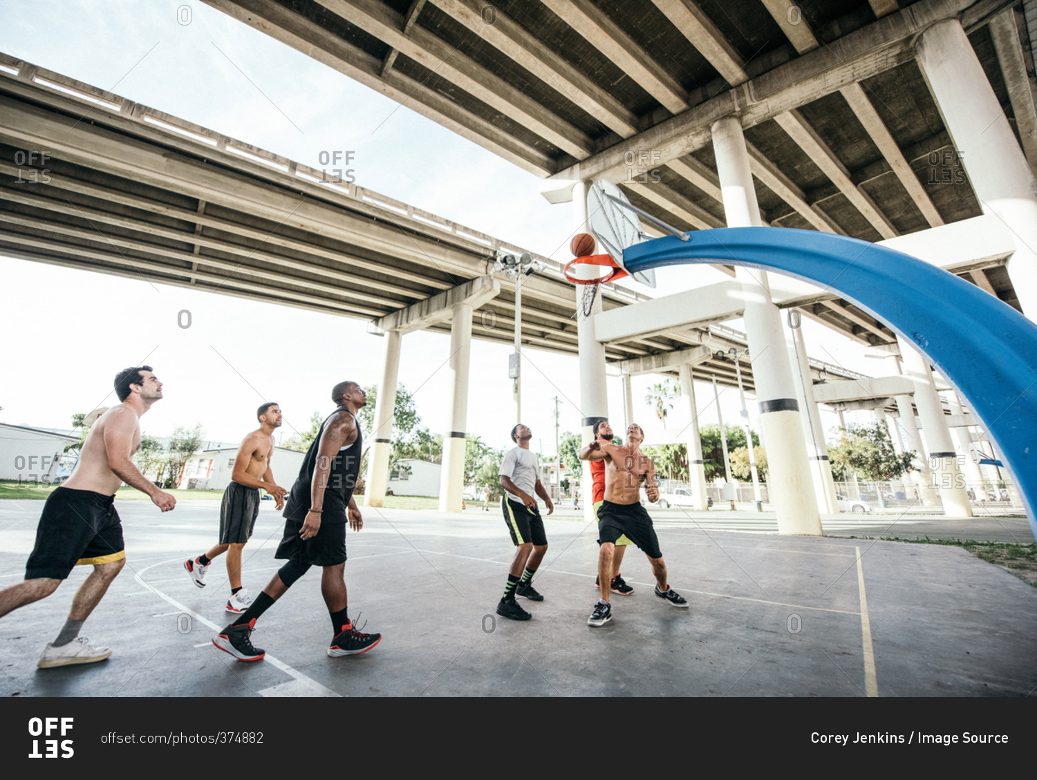 Men on basketball court watching basketball go through hoop