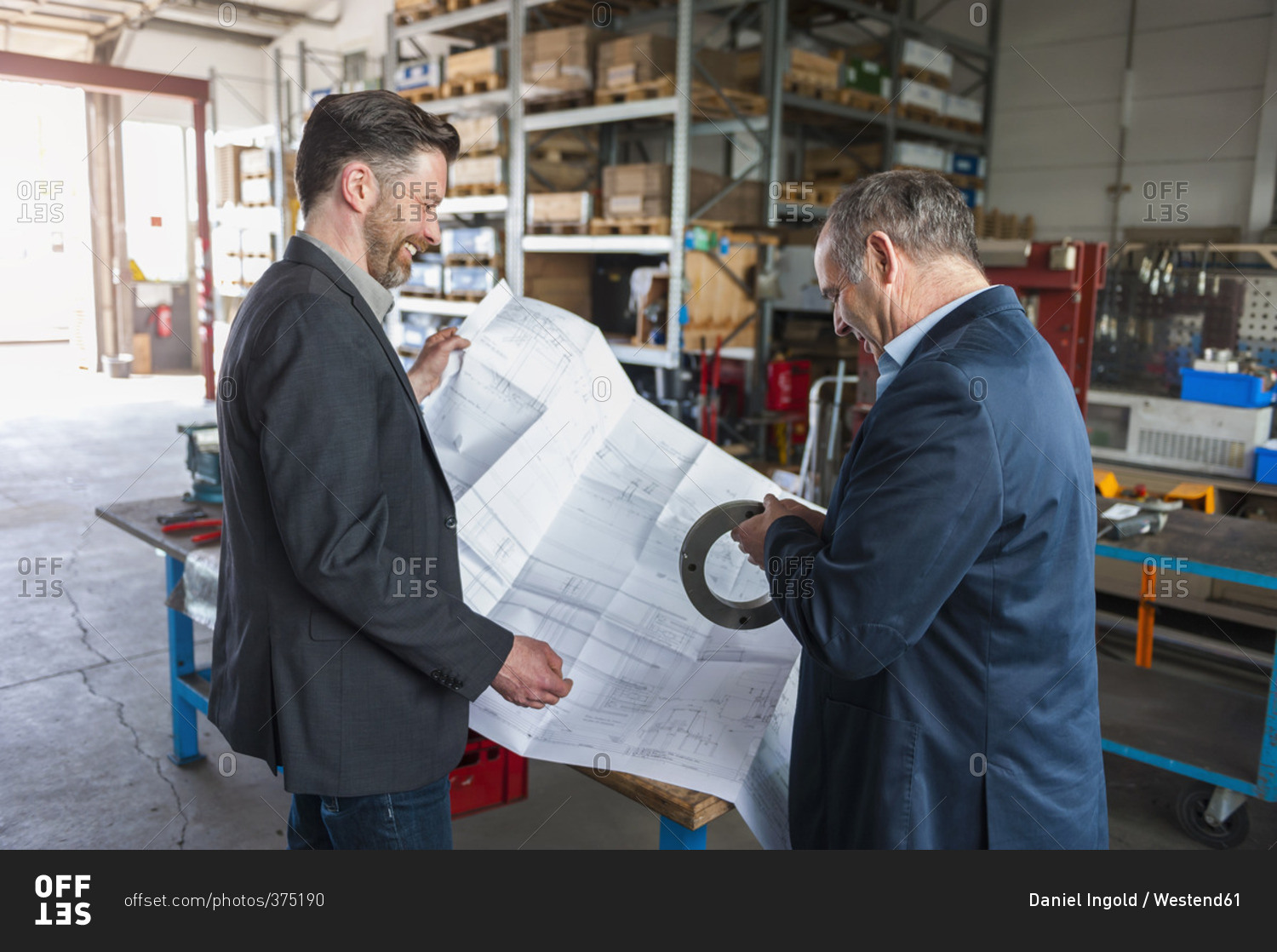 Two engineers with construction plan and hydraulic cylinder