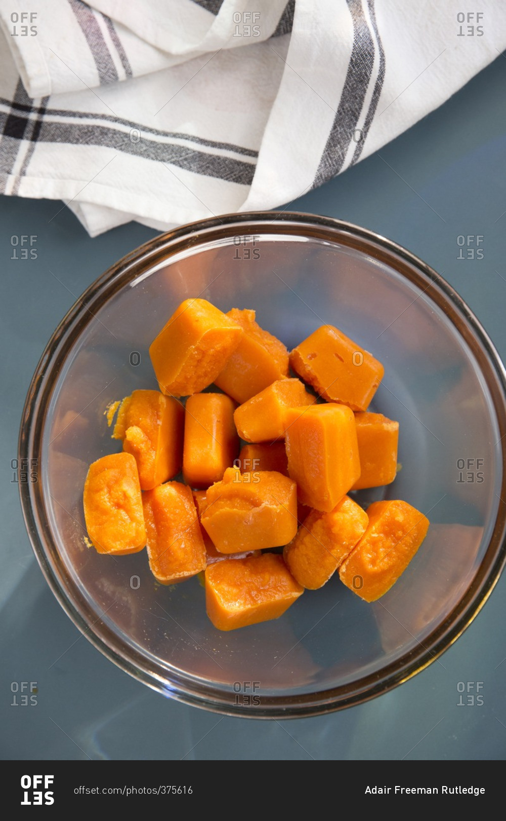 Frozen cubes of homemade baby food made from carrots in a glass bowl
