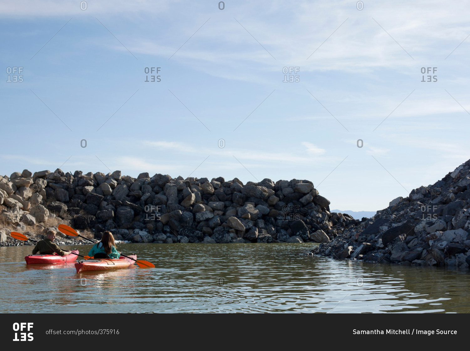 Rear view of kayakers sitting on water in kayaks facing rocks, Great Salt Lake, Utah, USA