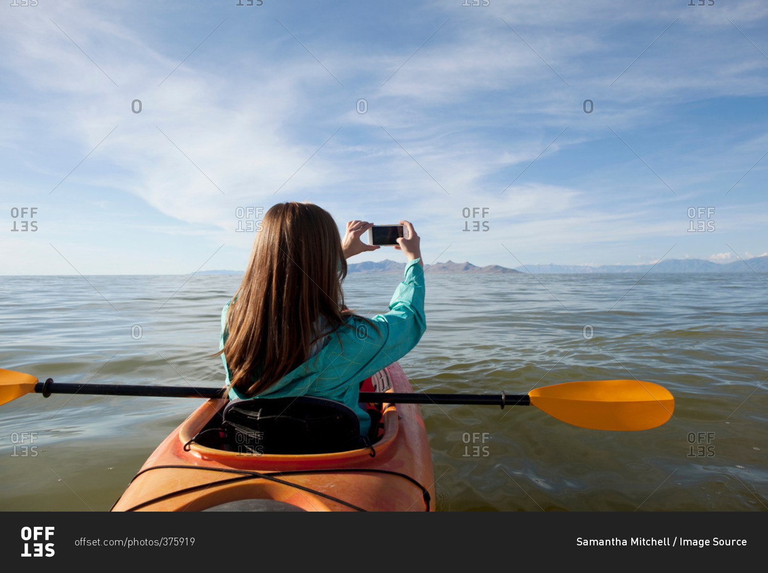 Rear view of young woman in kayak taking photograph, Great Salt Lake, Utah, USA