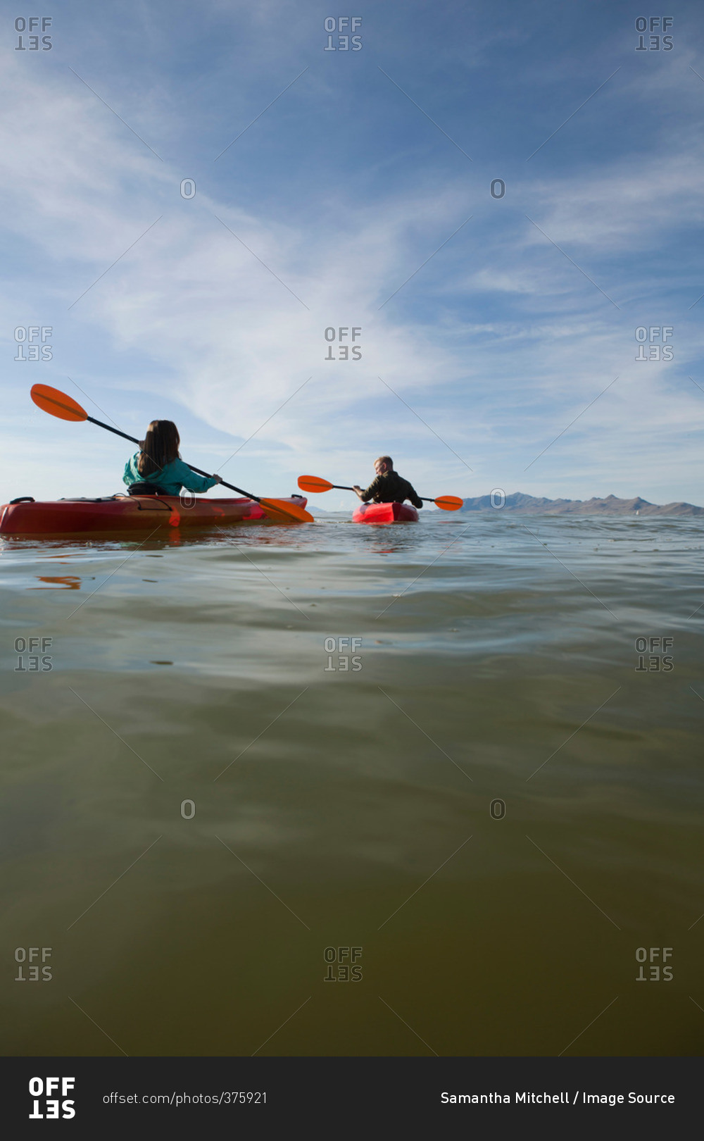 Rear view of young couple in kayaks holding paddles, Great Salt Lake, Utah, USA