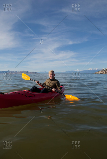 Young man in kayak holding paddles, looking at camera, Great Salt Lake, Utah, USA