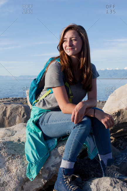 Young woman sitting on rocks, leaning on elbows, looking away, Great Salt Lake, Utah, USA