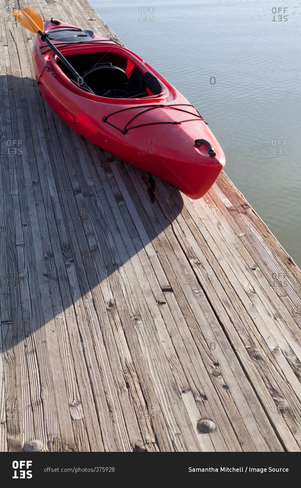 High angle view of kayak and paddle on wooden pier next to water