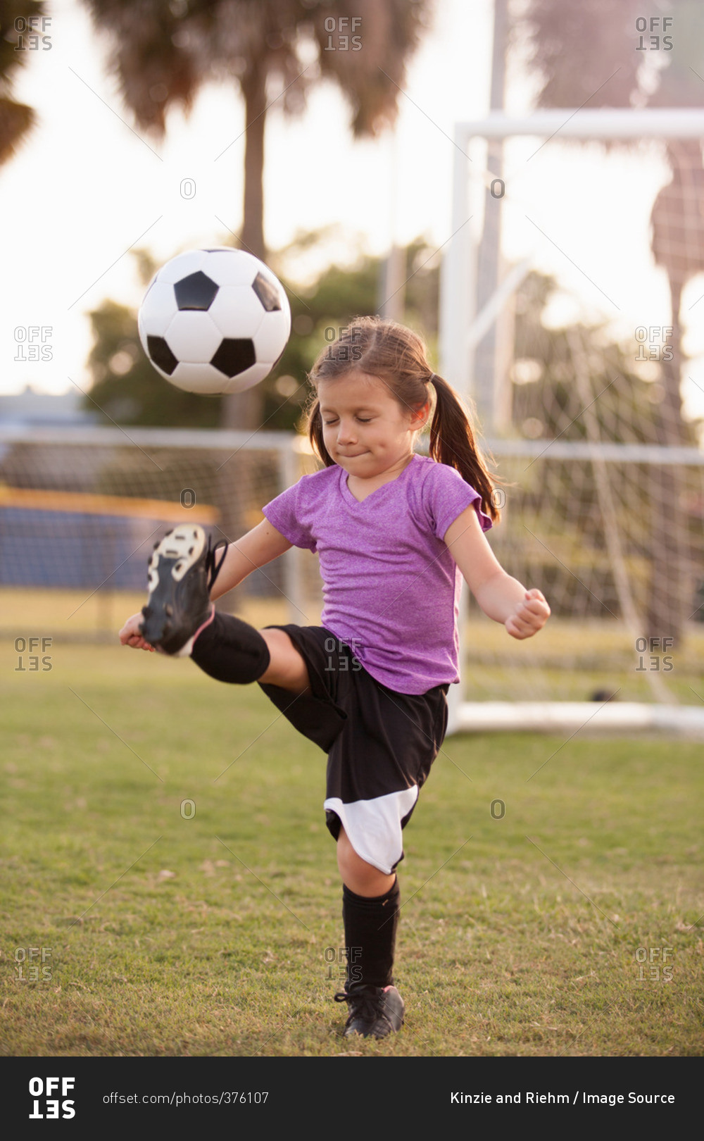Girl kicking football on practice pitch