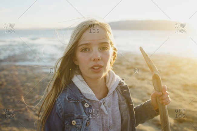 Portrait of a girl standing on a beach with a walking stick