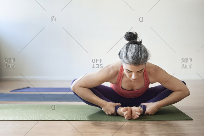 Mid adult woman performing yoga in bound angle pose at gym