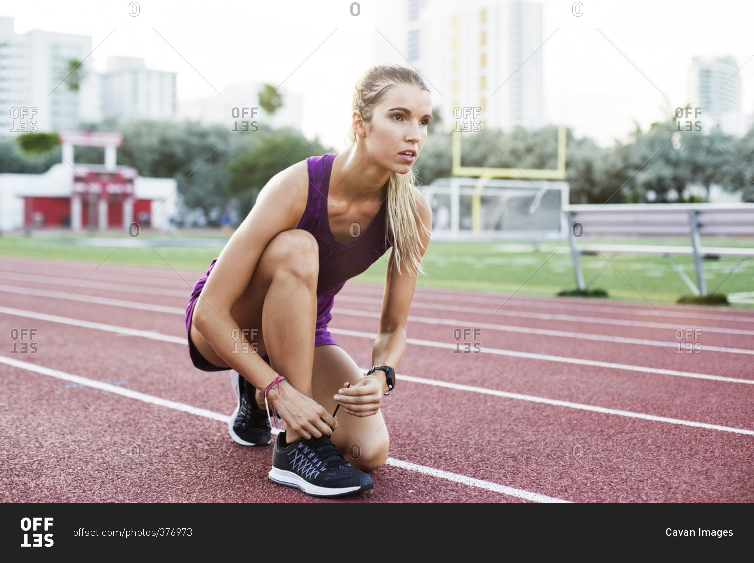 Confident female athlete tying shoelace on race tracks