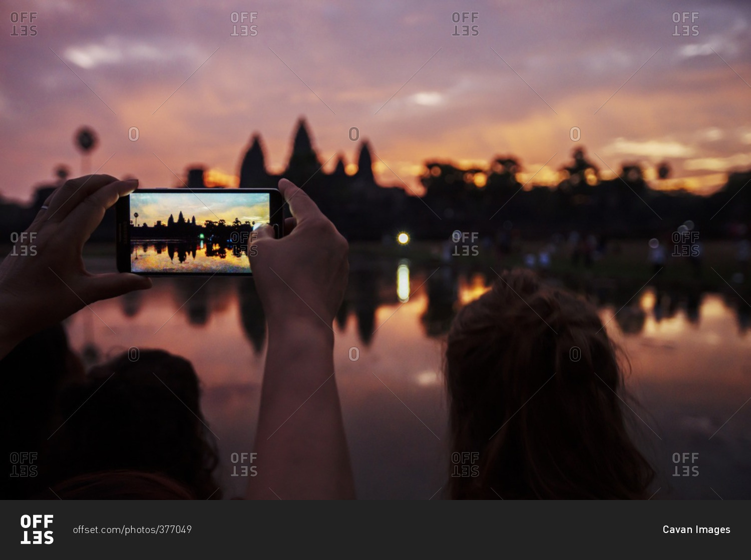 Cropped image of tourist photographing silhouette Angkor Wat temple during sunset