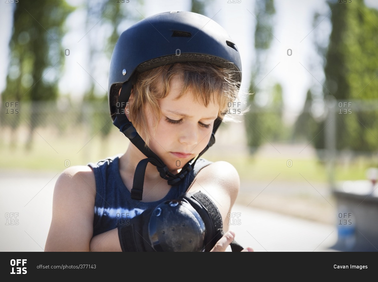 Boy adjusting elbow brace at skateboard park