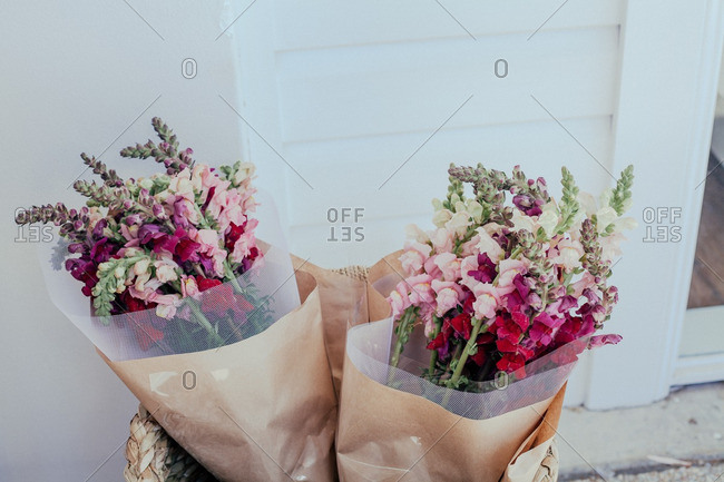 Two flower bouquets in a basket outside a door