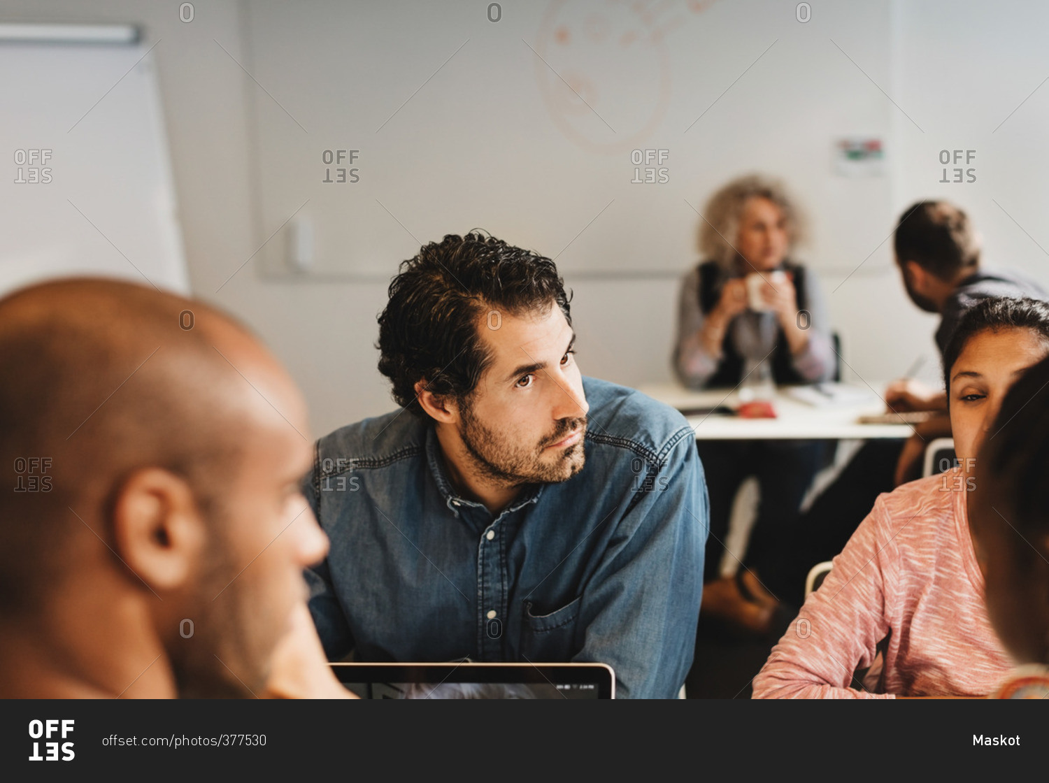 Friends discussing while man sitting with teacher at language class