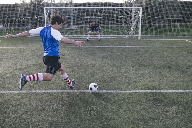 Soccer Player Kicking A Ball In Front Of A Goal With A Goalkeeper Stock Photo Offset