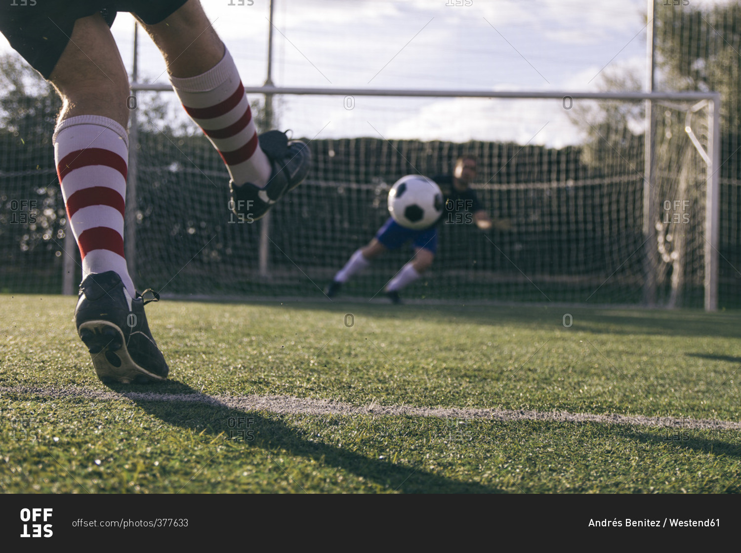 Legs Of A Soccer Player Kicking A Ball In Front Of A Goal With A Goalkeeper Stock Photo Offset