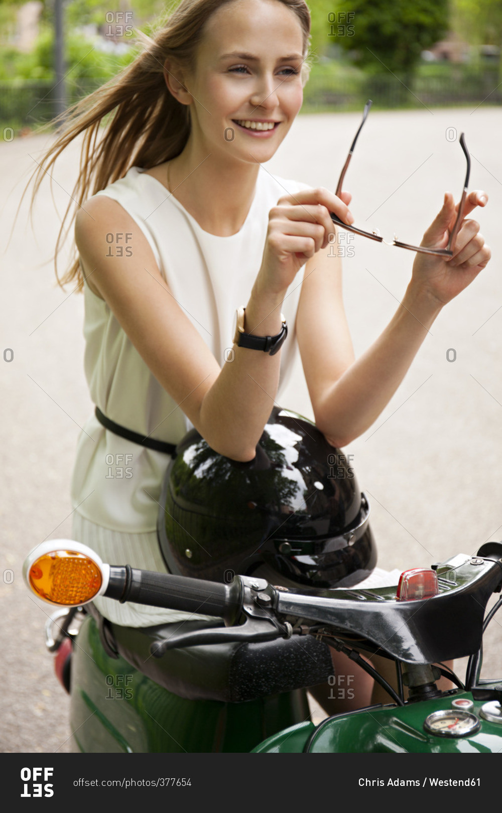 Portrait of smiling young woman with moped and motorcycle helmet