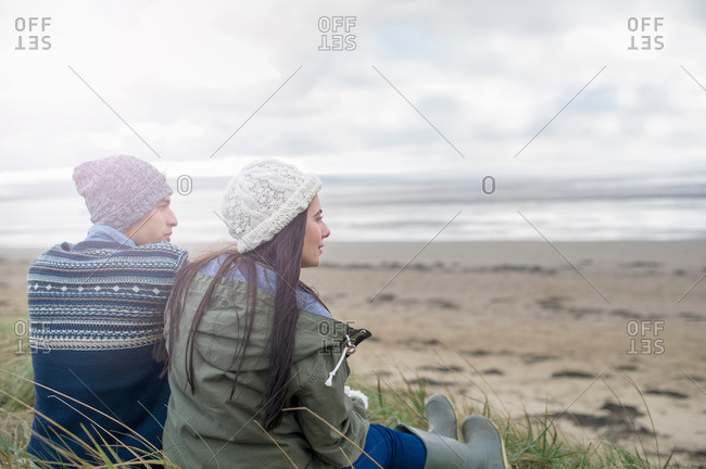 Young couple sitting on beach, Brean Sands, Somerset, England
