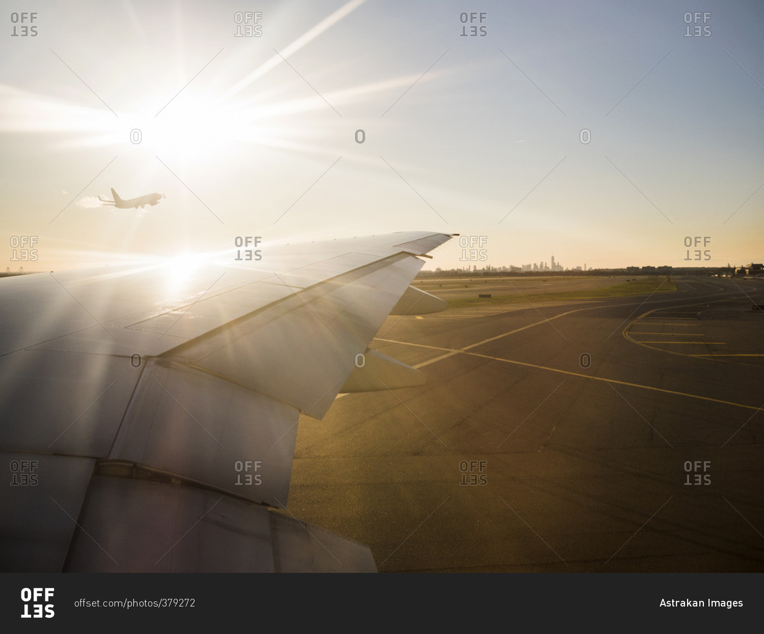 Cropped image of airplane on airport runway against shining sun