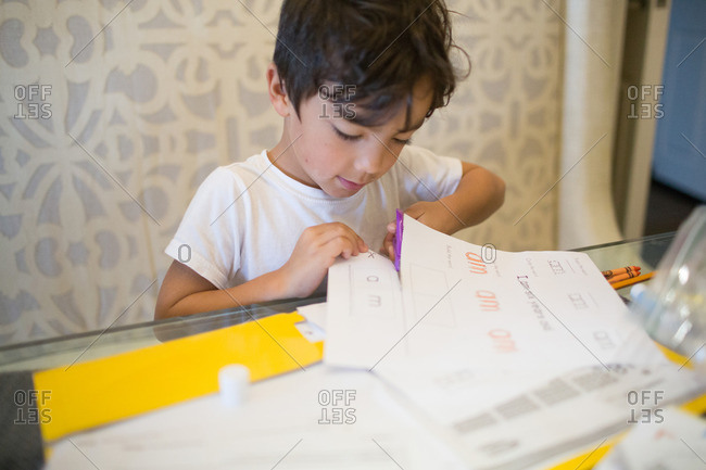 Young boy cutting paper at table