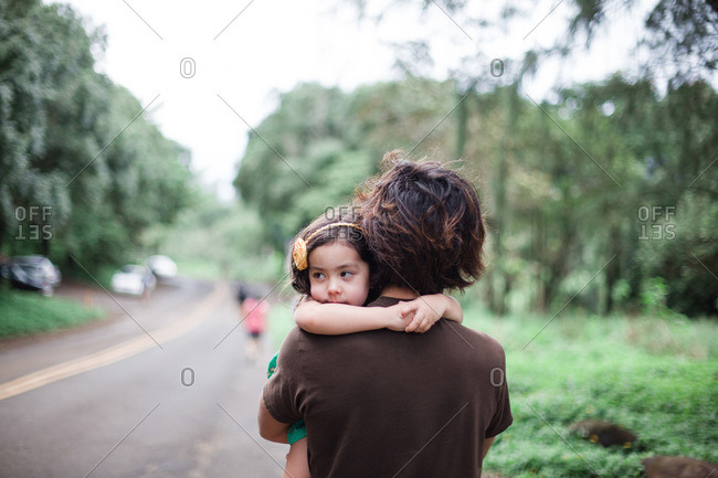 Young girl being carried by her father as they walk down a road