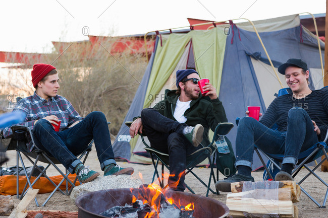 Three young male friends sitting chatting around campfire, Anza-Borrego Desert State Park, California, USA