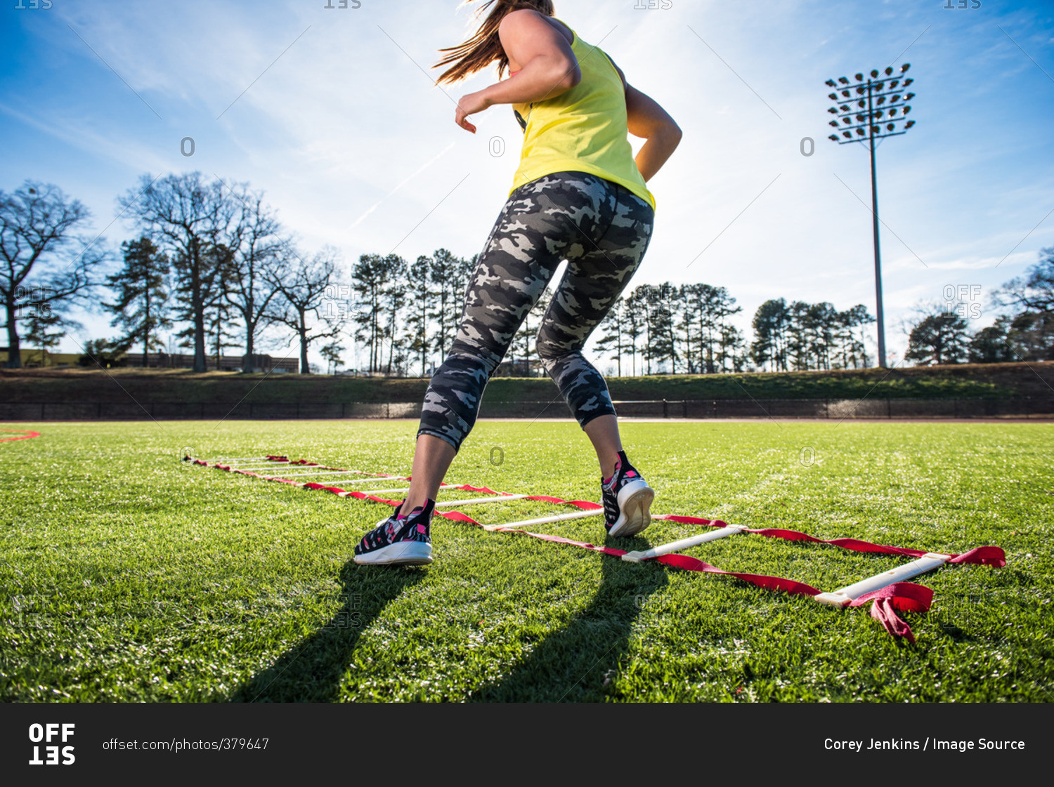 Female athlete training with agility ladder on sports field