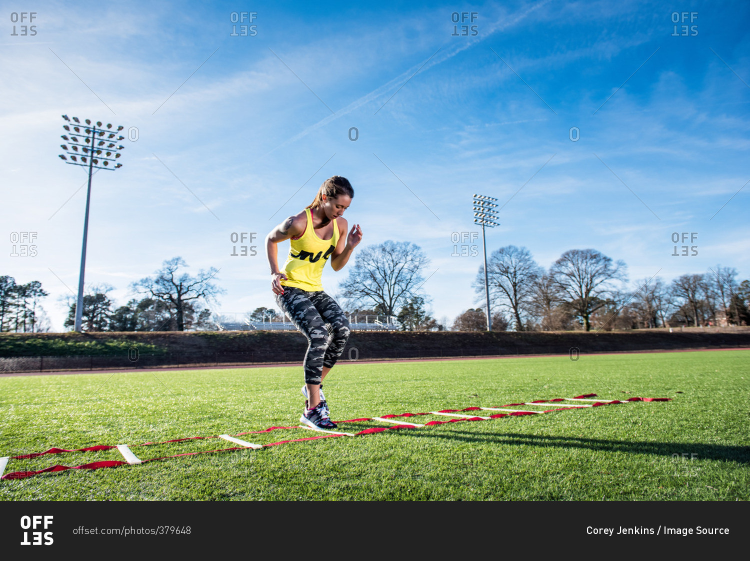 Young female athlete training with agility ladder on sports field