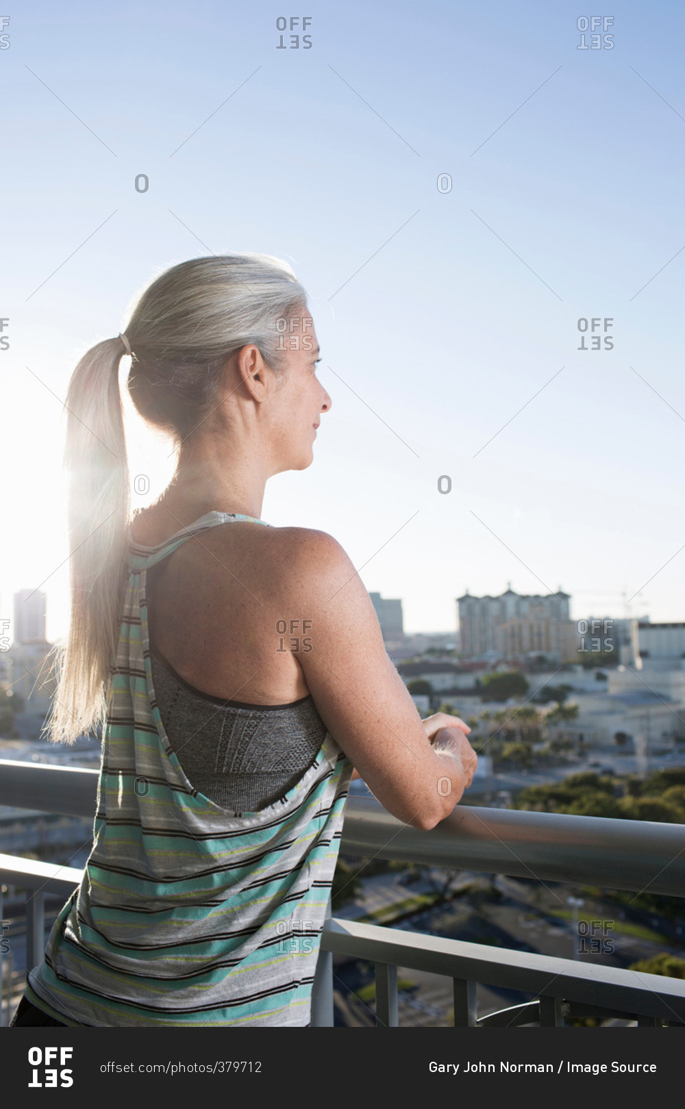 Mature woman in sports clothing leaning against city balcony
