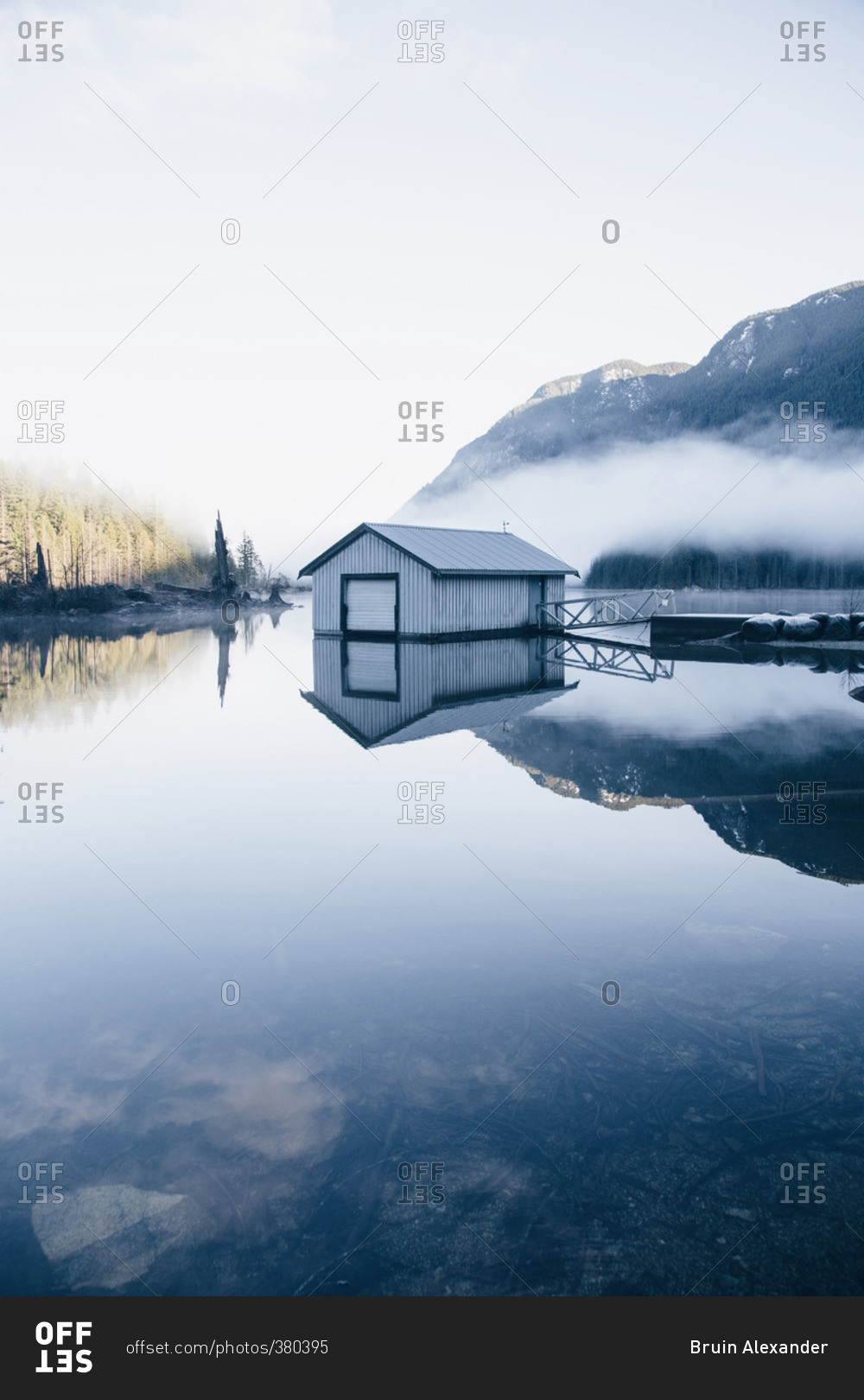 Boat house beneath foggy mountains