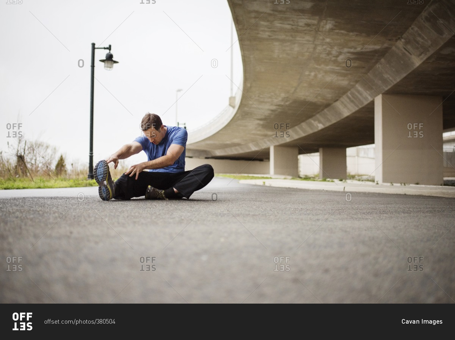 Determined man exercising while sitting on street
