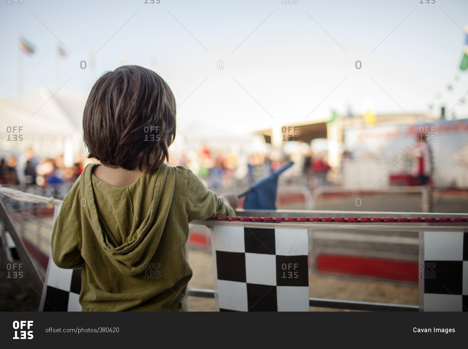 Rear view of boy standing by railing at amusement park