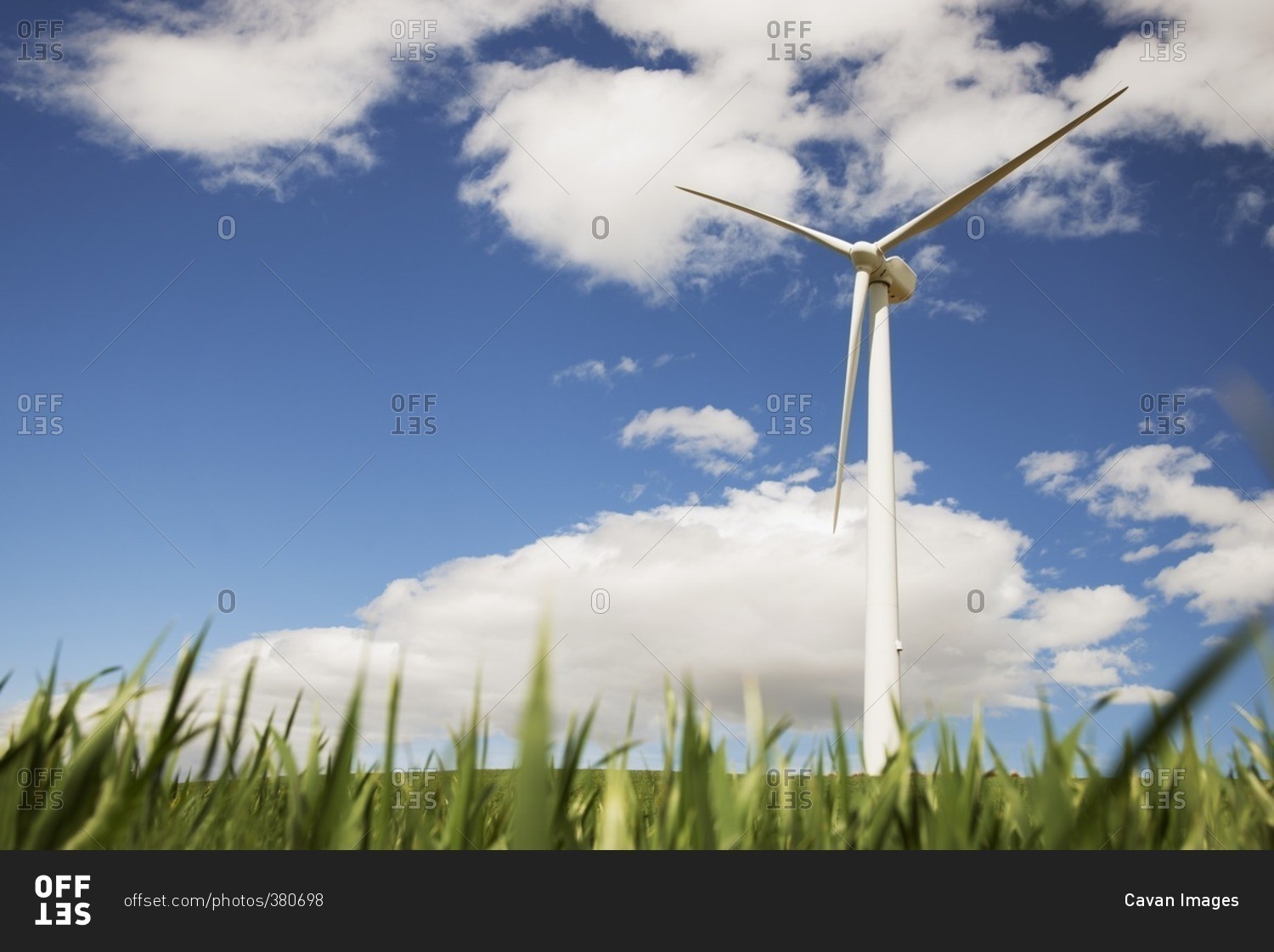 Low angle view of wind turbine on grassy field against sky