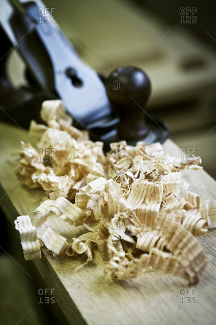 A wood plane on a piece of wood and wood shavings