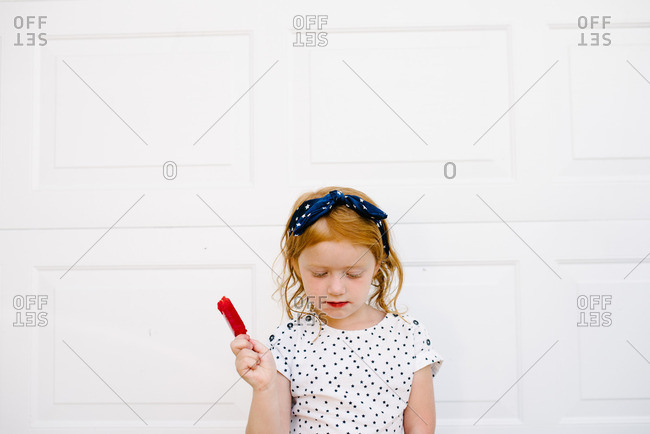 Little girl holding a red frozen popsicle stock photo - OFFSET