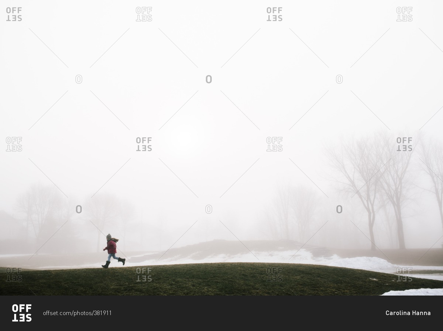 Girl walking across a field on a cold, foggy day