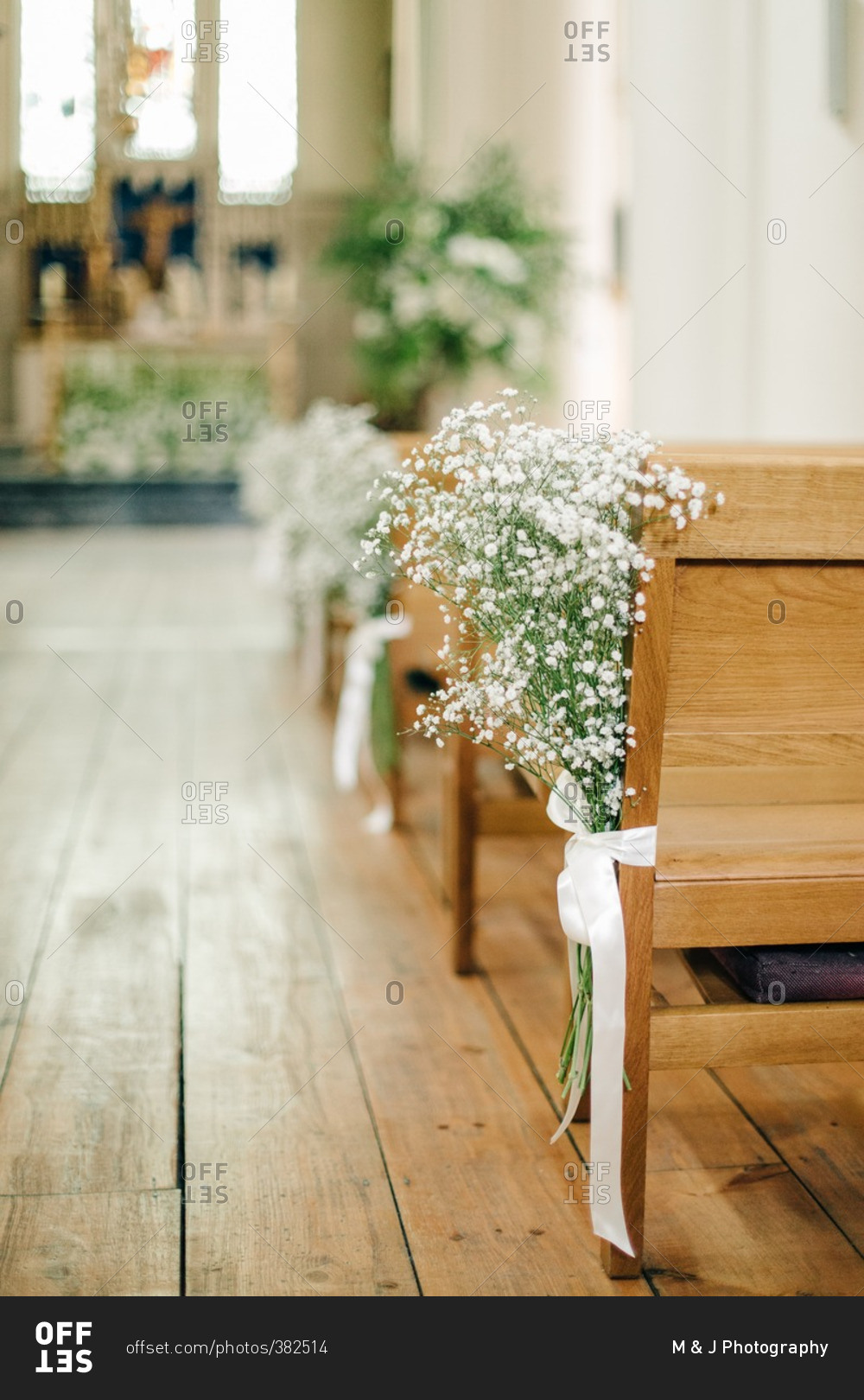 Baby's breath bouquets tied to the end of wood church pews in a wedding chapel