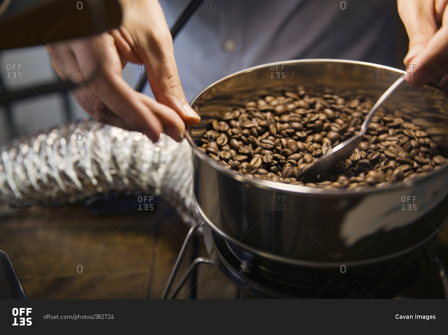 Midsection of man roasting coffee beans in machinery at cafe