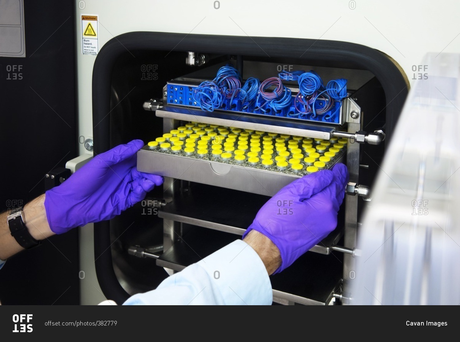 Scientist inserting medical sample tray in machinery