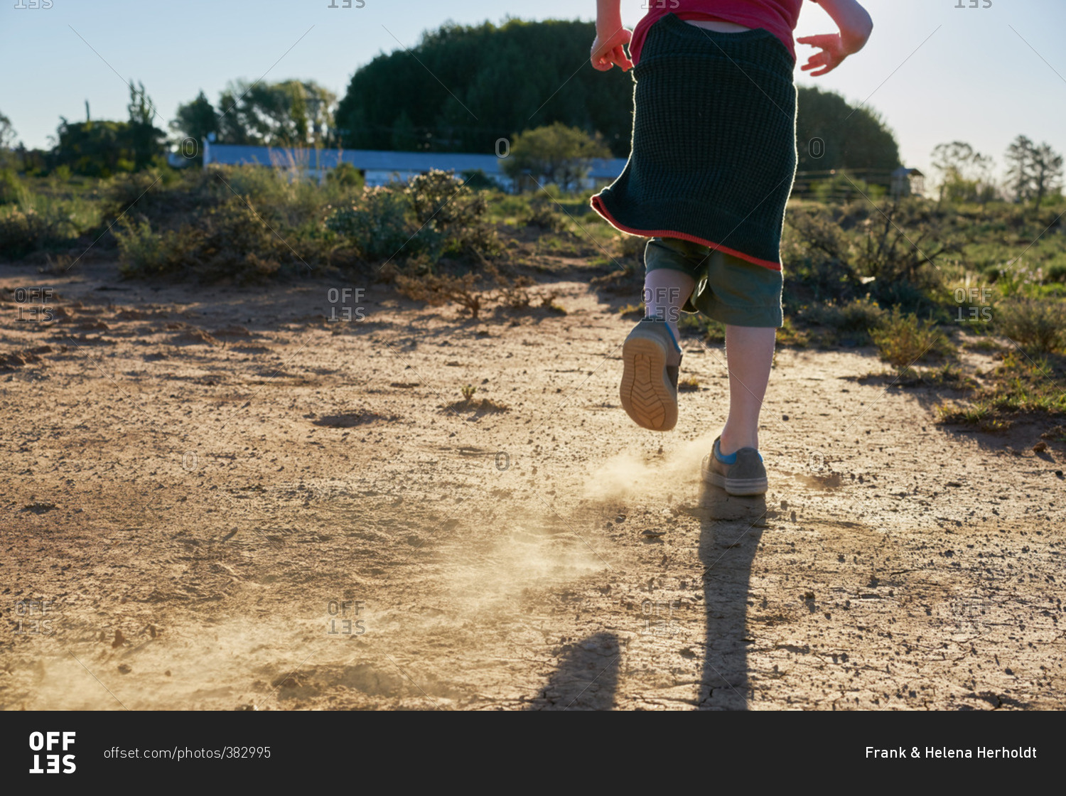 Boy kicking up dirt on a dirt patch in a scrubland
