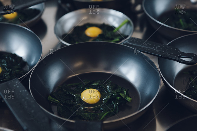 Egg yolks over greens in a saute pan