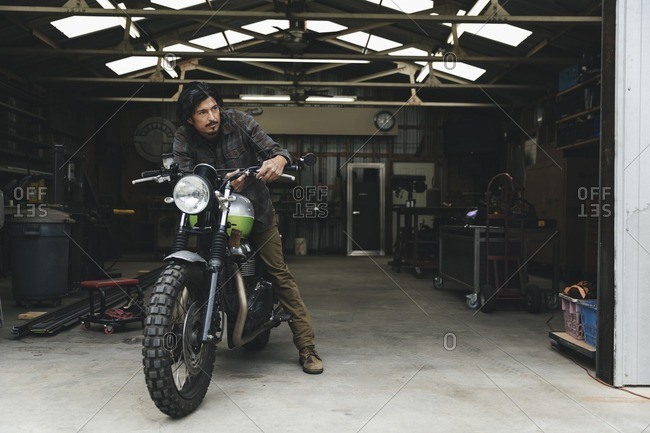 Man sitting on a motorcycle in an automotive repair shop