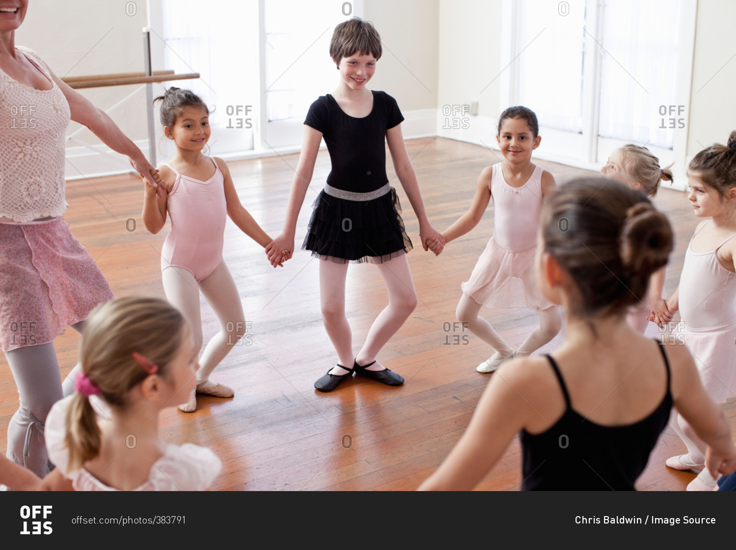 Children and teacher in a circle practicing ballet in ballet school