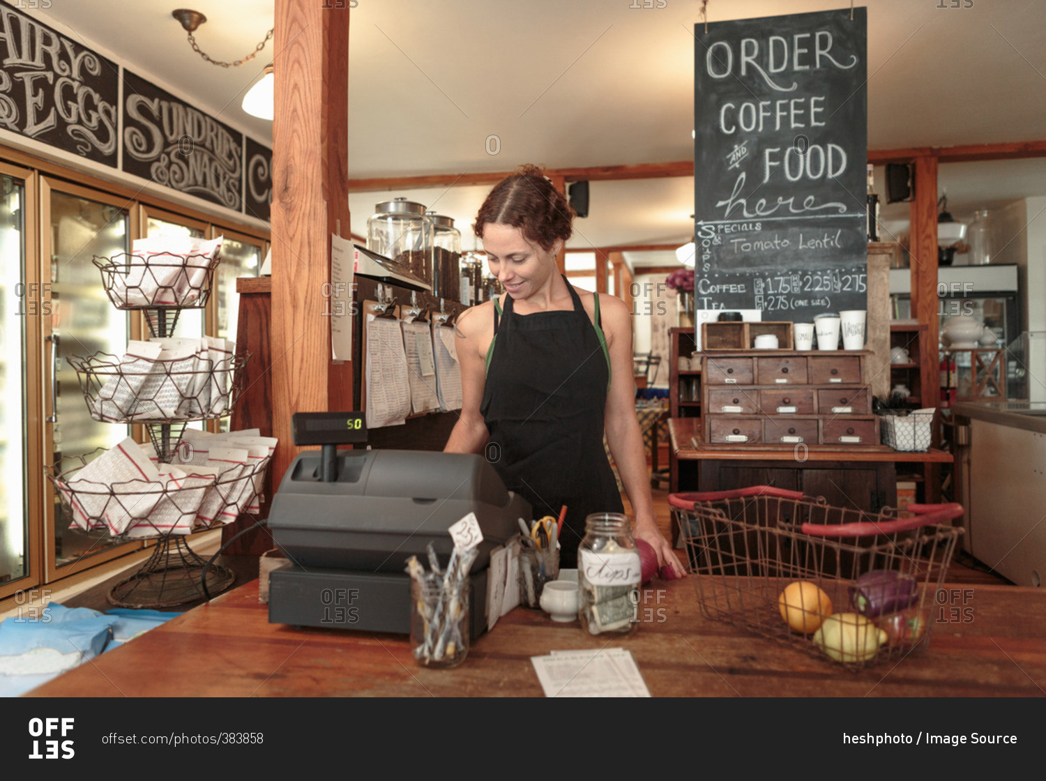 Female sales assistant using check out till in country store cafe