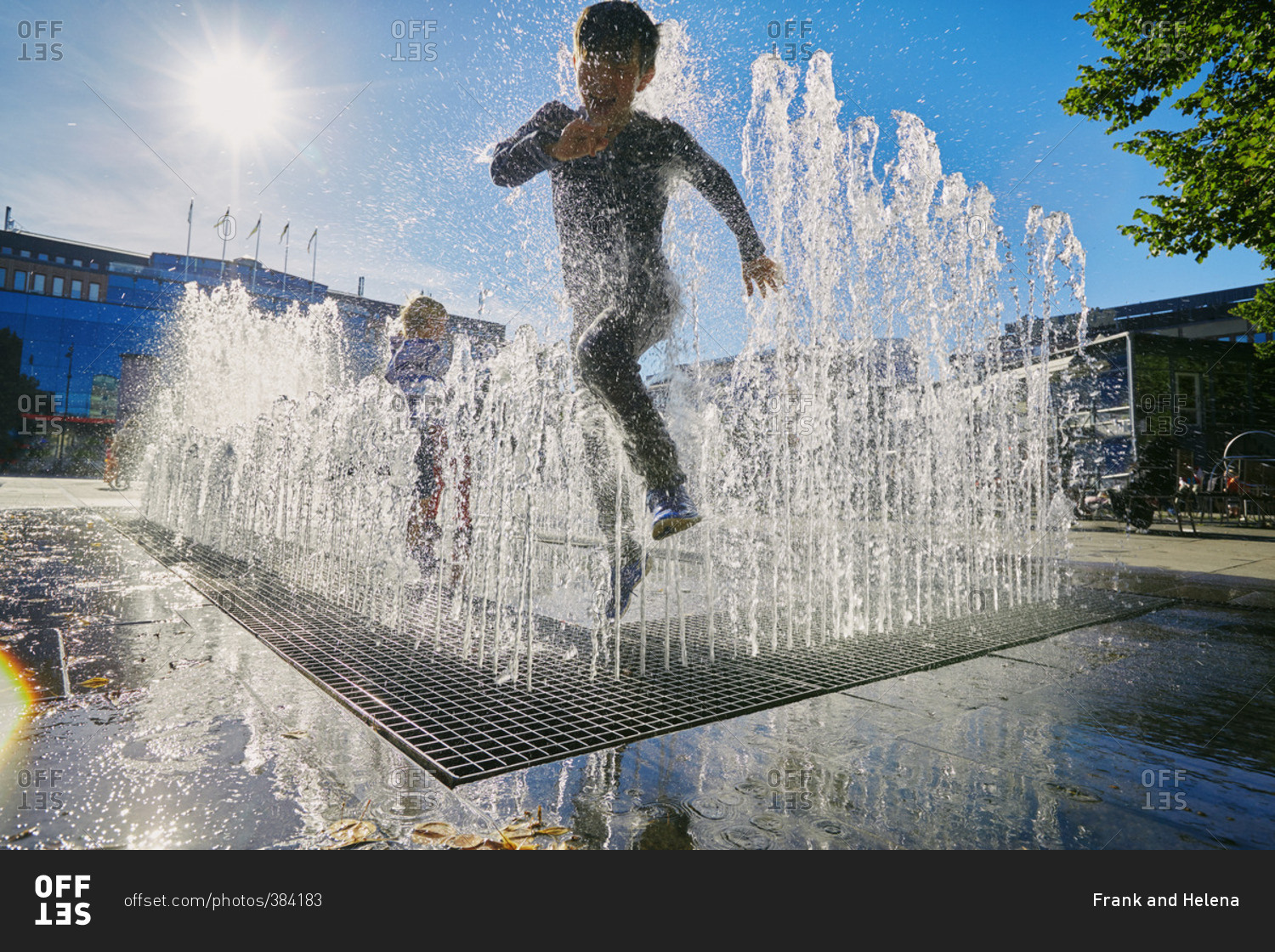 Boy jumping in city fountain
