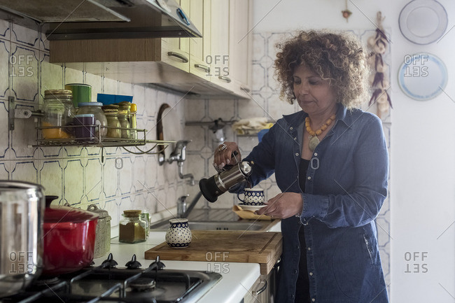 Woman at home pouring coffee into cup