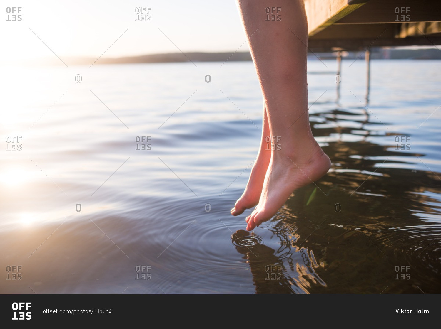 Woman's feet dangling over water stock photo OFFSET