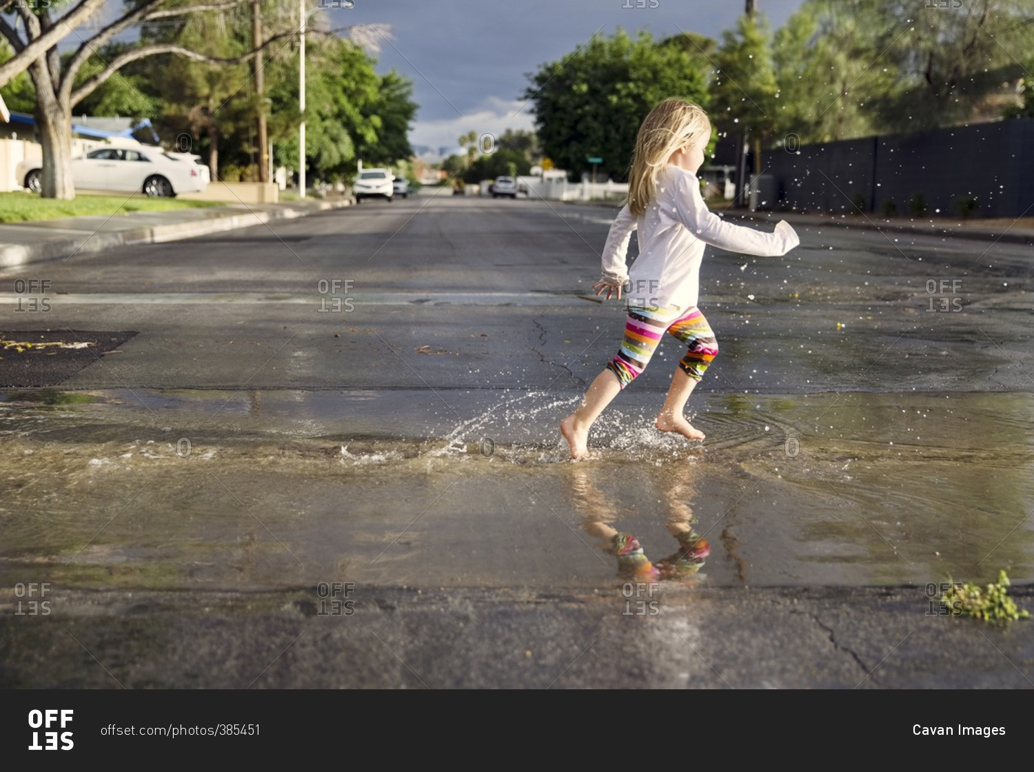 Side view of girl running on wet street during rainy season