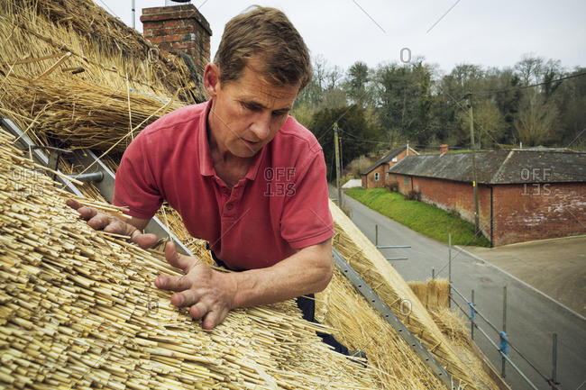 Man thatching a roof, layering the straw