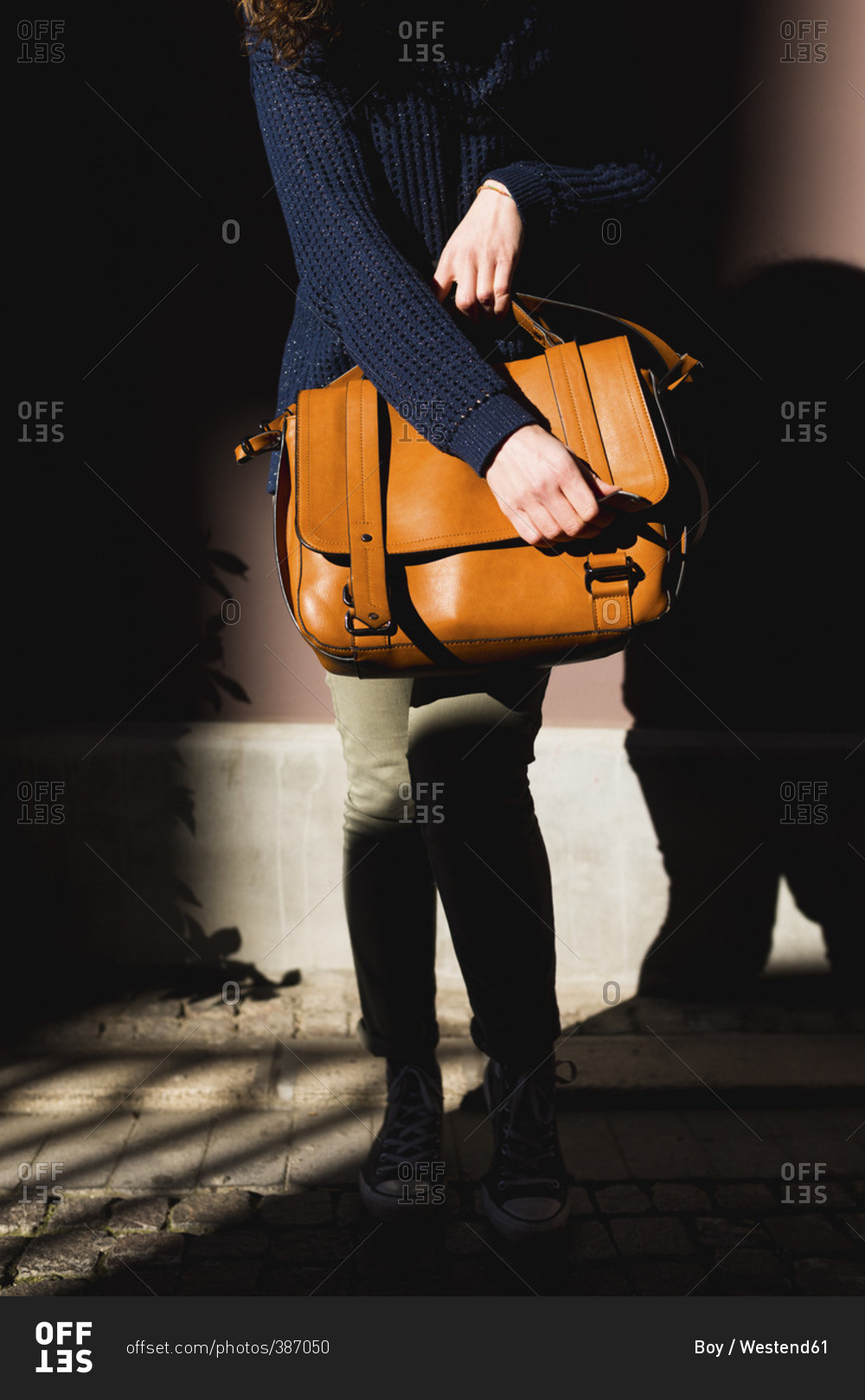 Woman carrying leather bag, partial view
